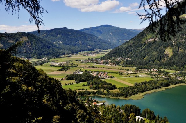 Panoramic view to Carinthia, Austria. A part of Lake Oaaiach situated next to meadows and fields.