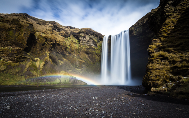 Sunlight creates a rainbow in the spray of Skogafoss, Iceland